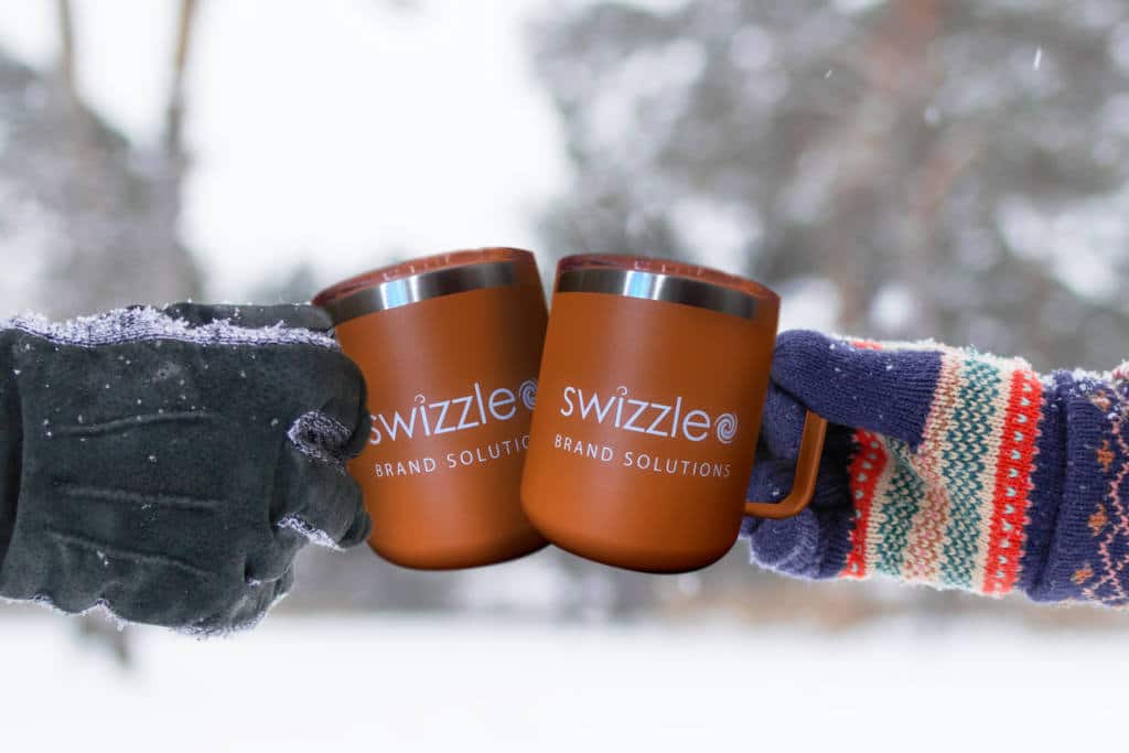 Two metal cups with hot tea in hands man's and woman's on a background of winter forest.