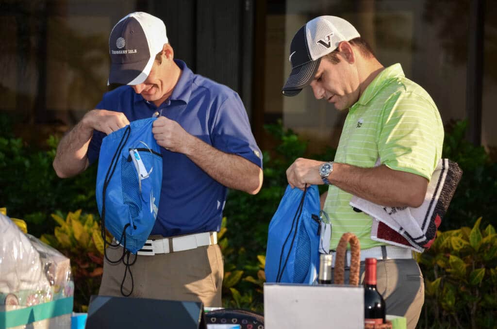 Palm Beach Gardens, FL, USA - May 18, 2013: Two men dressed in golf attire standing behind a table of gifts at a charity golf event benefiting juvenile diabetes. They are looking into their goody bags.